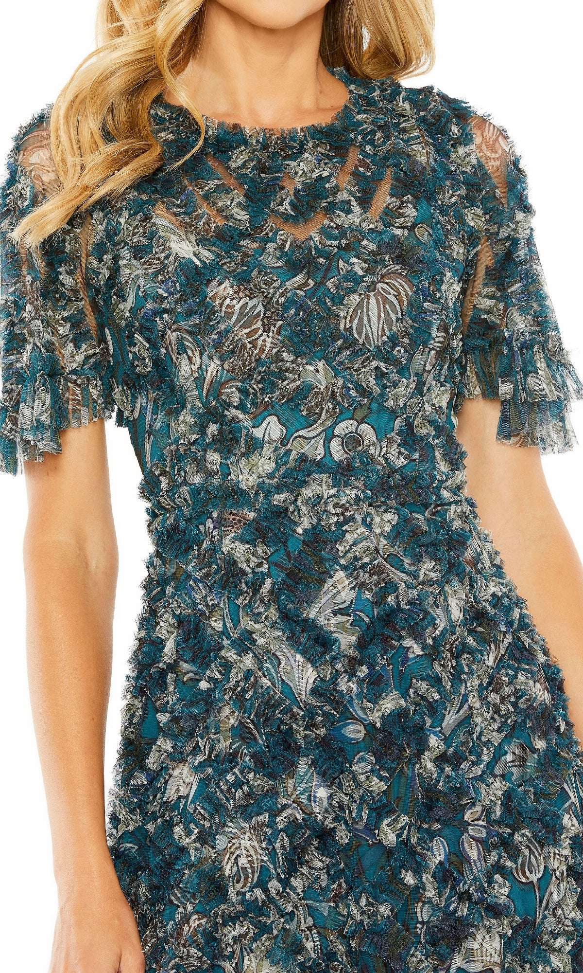 A woman models the Mac Duggal 8043 Long Formal Dress—a teal, textured short-sleeve dress with floral pattern and sheer panels—shown from shoulders to mid-thigh.
